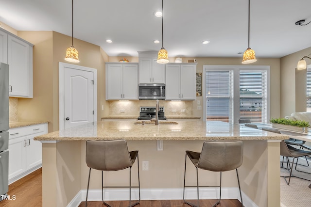 kitchen with a sink, stainless steel appliances, tasteful backsplash, and a breakfast bar