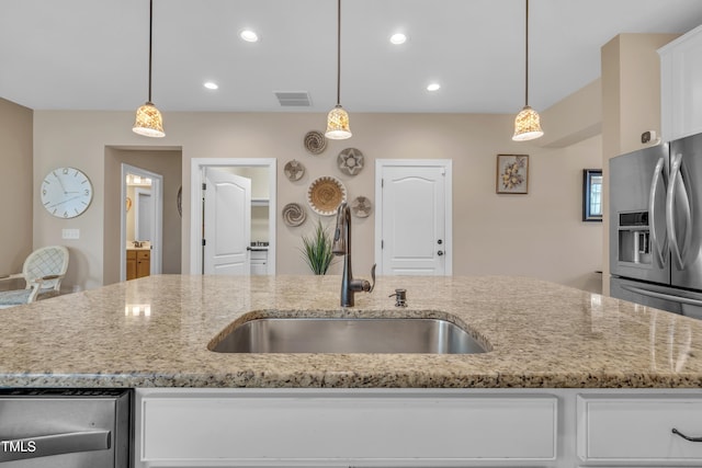 kitchen with a sink, light stone countertops, recessed lighting, and white cabinetry