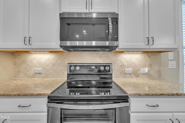 kitchen featuring light stone counters, stainless steel appliances, backsplash, and white cabinetry