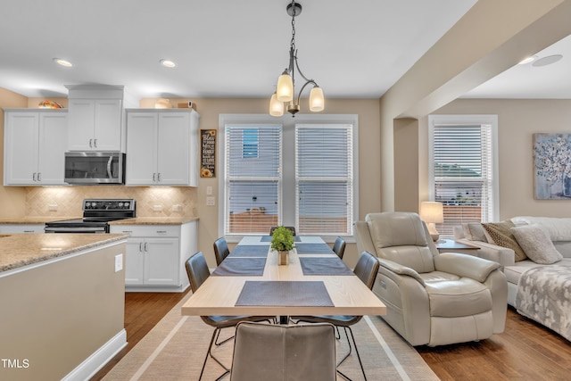 kitchen with stainless steel microwave, black electric range oven, open floor plan, and wood finished floors