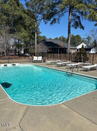 community pool with a patio area and fence