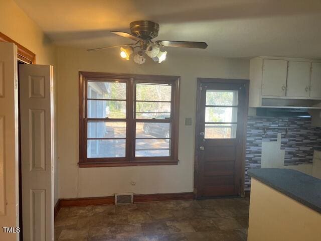 entryway with visible vents, stone finish floor, baseboards, and a ceiling fan