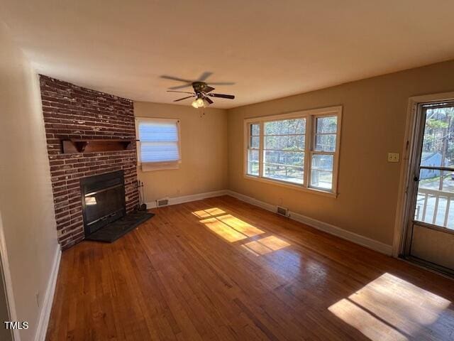 unfurnished living room with wood finished floors, visible vents, and baseboards