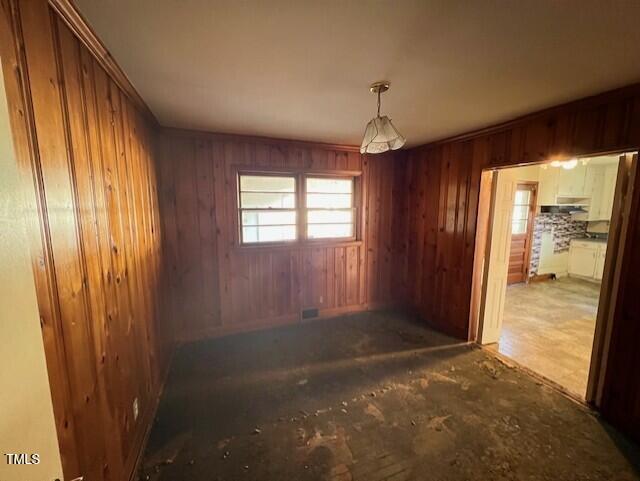 empty room featuring visible vents and wood walls