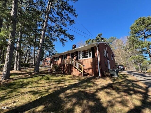 view of side of home with brick siding and a yard