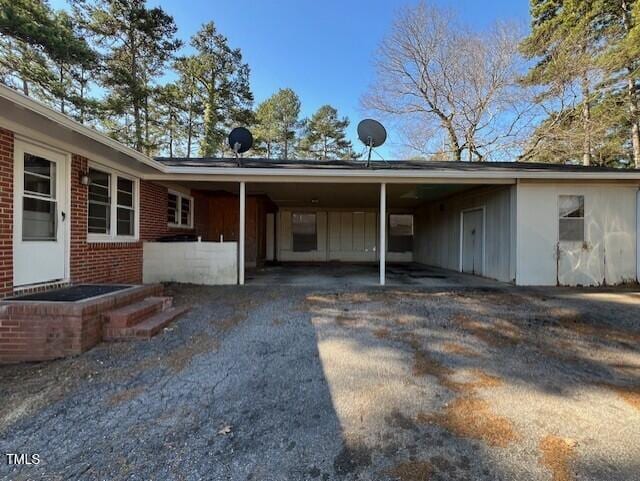 exterior space with a carport, driveway, and brick siding