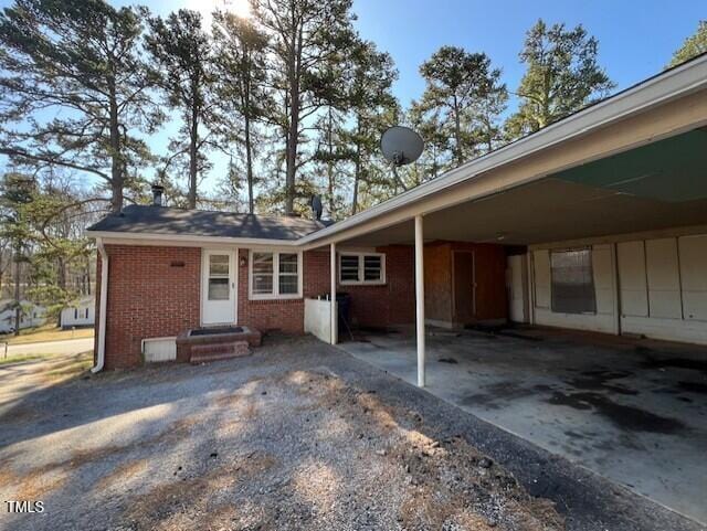 exterior space featuring entry steps, a carport, brick siding, and driveway