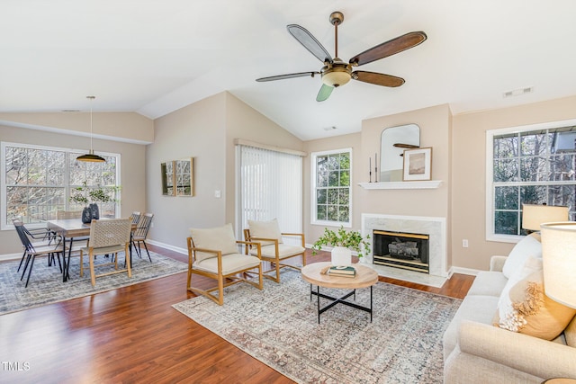 living room with wood finished floors, visible vents, a fireplace, ceiling fan, and vaulted ceiling