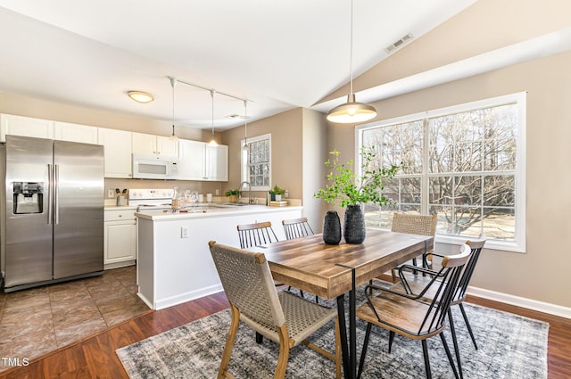 dining room featuring visible vents, track lighting, dark wood finished floors, baseboards, and vaulted ceiling