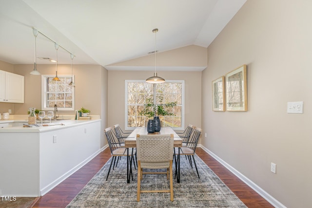 dining room featuring dark wood-style floors, visible vents, baseboards, and vaulted ceiling