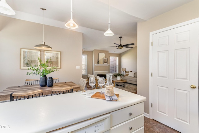 kitchen featuring ceiling fan, light countertops, a fireplace, hanging light fixtures, and white cabinetry