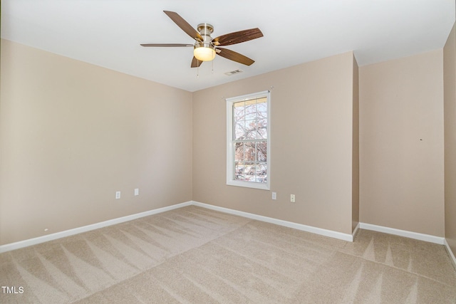 unfurnished room featuring visible vents, light colored carpet, a ceiling fan, and baseboards