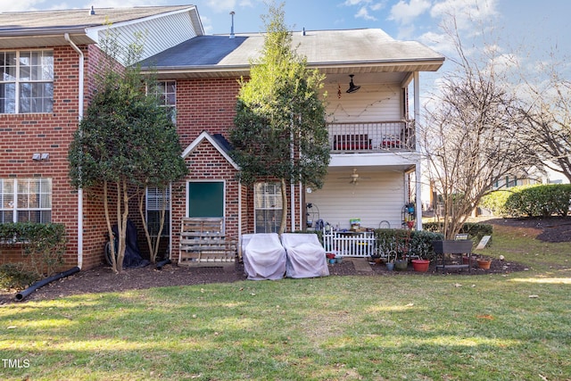 back of property with a balcony, a yard, and brick siding