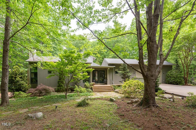 mid-century modern home featuring covered porch and driveway