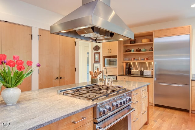 kitchen featuring light wood-style floors, island exhaust hood, premium appliances, and light stone countertops