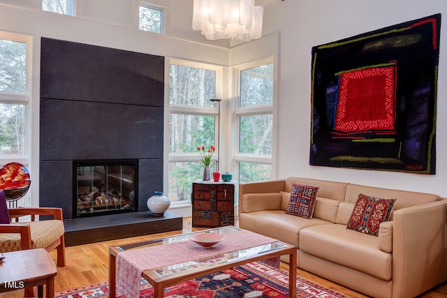 living area featuring a large fireplace, a notable chandelier, and wood finished floors