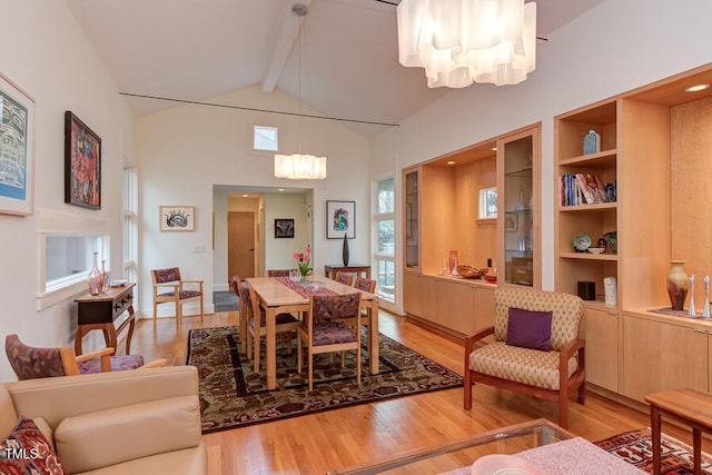 dining area with wood finished floors, beam ceiling, high vaulted ceiling, and a chandelier