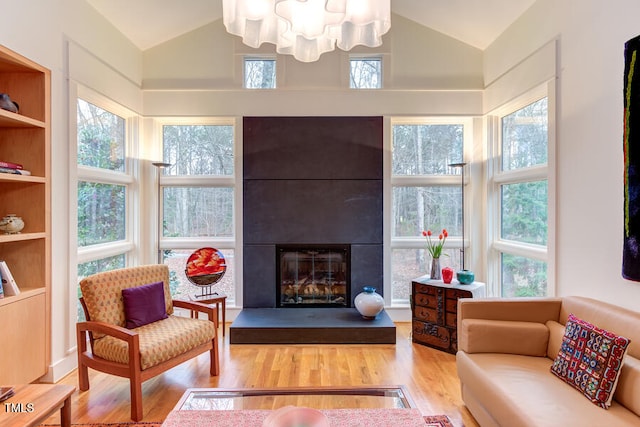 living room with a wealth of natural light, a fireplace, lofted ceiling, and wood finished floors