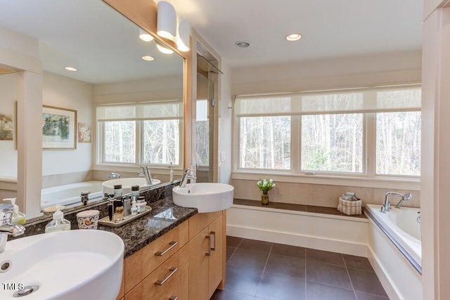 bathroom with tile patterned flooring, a garden tub, and a sink