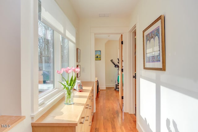 corridor with light wood-type flooring, plenty of natural light, and visible vents