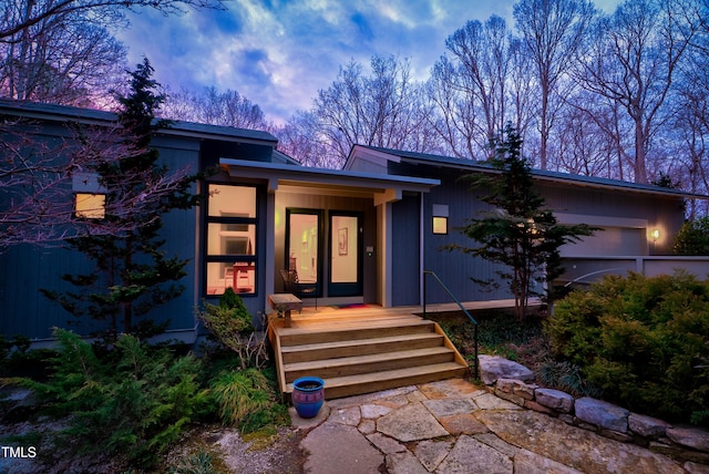 exterior entry at dusk featuring an attached garage