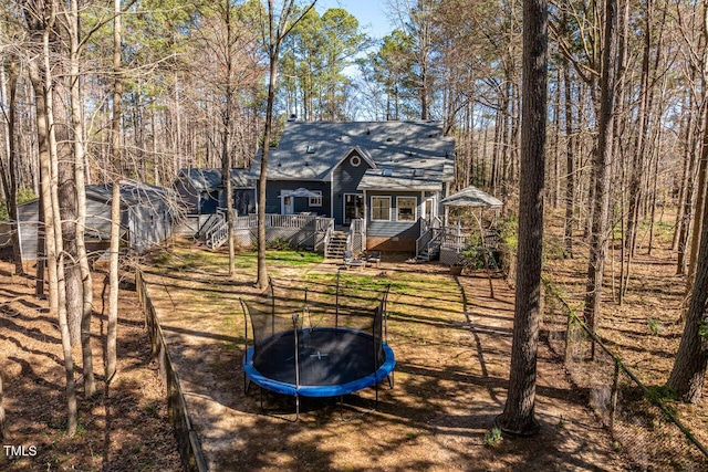 rear view of house featuring stairs, a trampoline, and a wooden deck