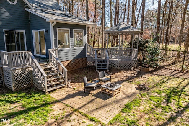 exterior space featuring a deck, a patio, a gazebo, a fire pit, and stairs