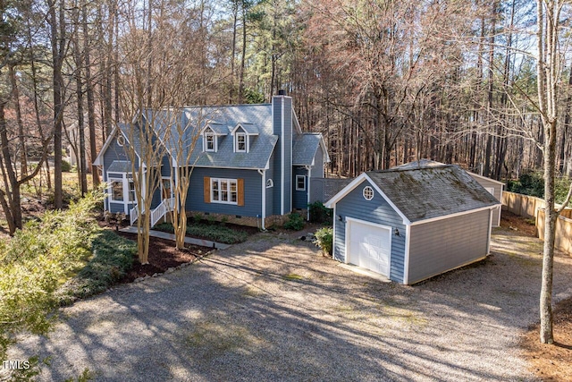 view of front facade with a detached garage, fence, a chimney, crawl space, and an outbuilding