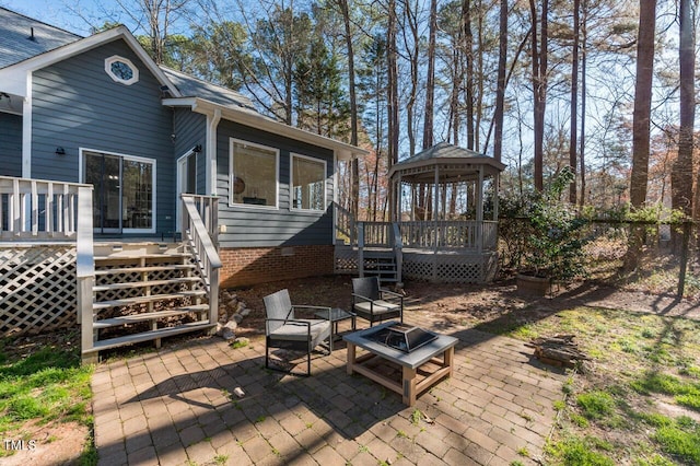 rear view of property with a wooden deck, an outdoor fire pit, stairs, a gazebo, and a patio