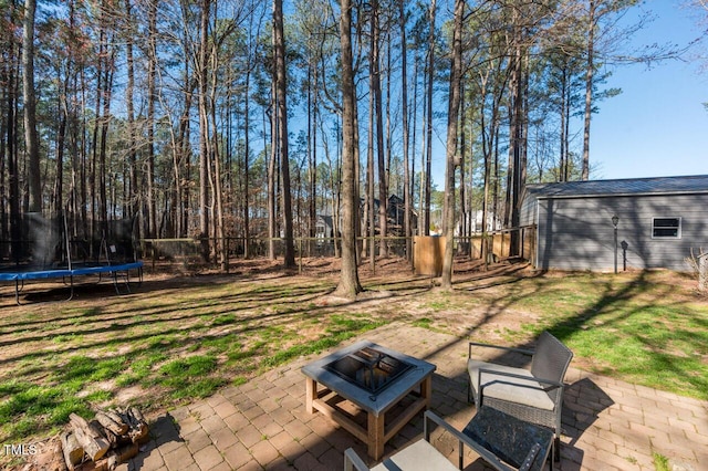 view of yard with a patio area, a trampoline, and an outdoor fire pit