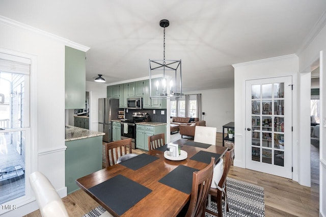 dining area featuring an inviting chandelier, crown molding, and light wood-type flooring