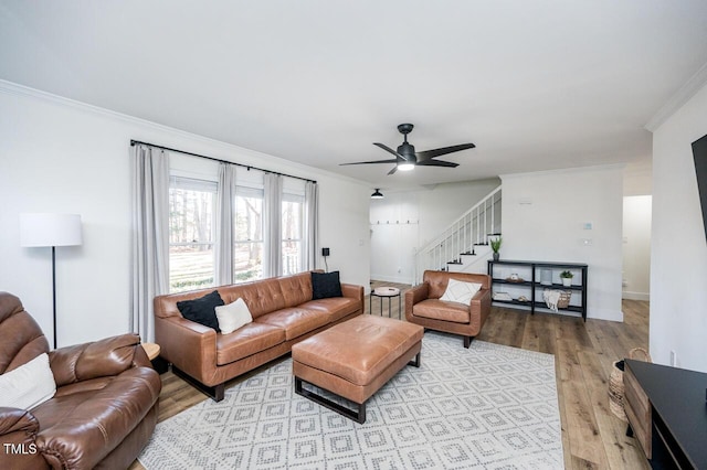 living area featuring light wood finished floors, stairway, crown molding, and ceiling fan