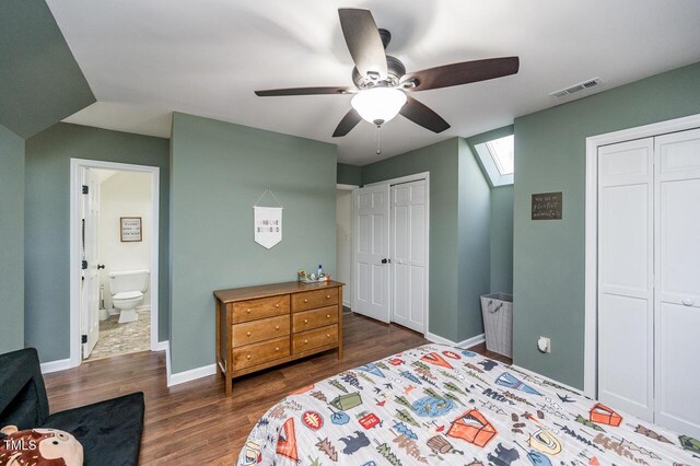 bedroom with visible vents, two closets, dark wood finished floors, a skylight, and baseboards