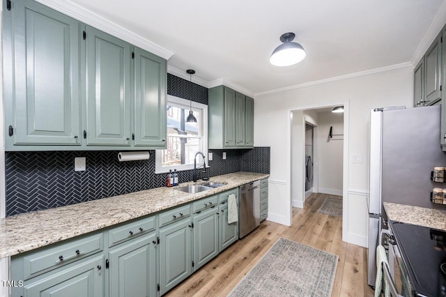 kitchen with a sink, stainless steel appliances, crown molding, light wood finished floors, and decorative backsplash