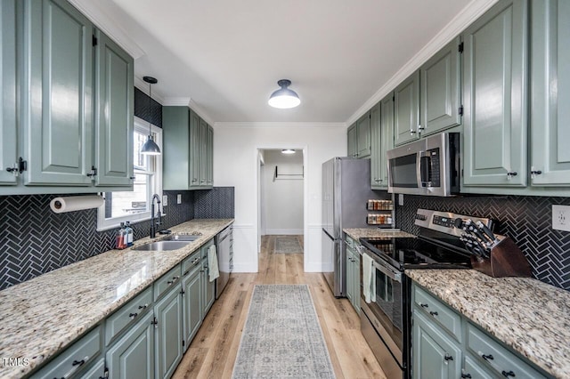 kitchen with light wood-style flooring, a sink, decorative backsplash, ornamental molding, and stainless steel appliances