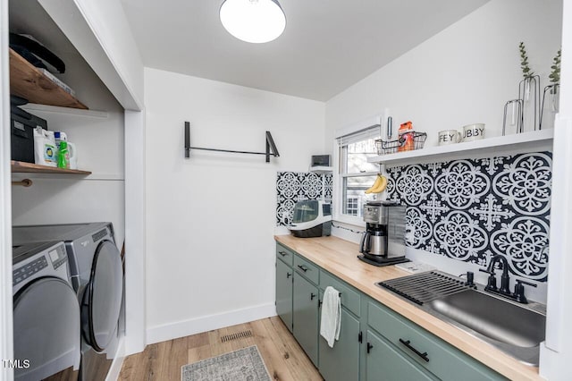 laundry room with light wood-style flooring, a sink, washer and dryer, baseboards, and laundry area