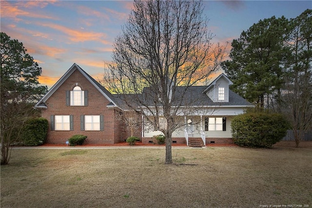 view of front facade with crawl space, a porch, brick siding, and a front yard