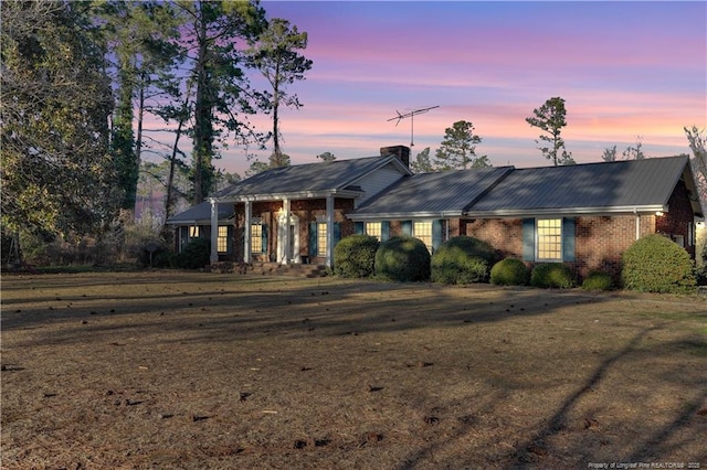 view of front of home featuring brick siding and metal roof