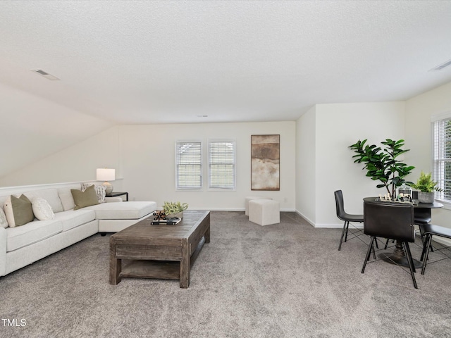 carpeted living area with vaulted ceiling, baseboards, visible vents, and a textured ceiling