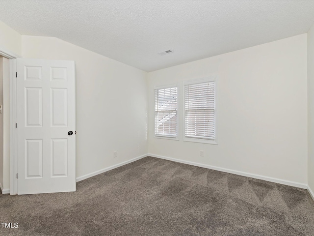 empty room with visible vents, baseboards, dark colored carpet, and a textured ceiling