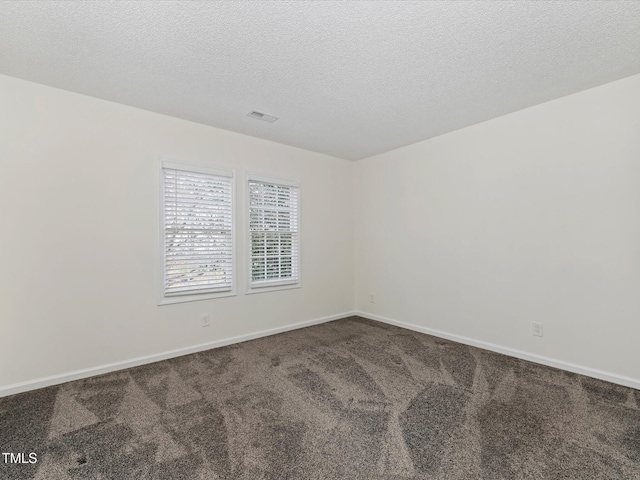 spare room featuring carpet flooring, baseboards, visible vents, and a textured ceiling