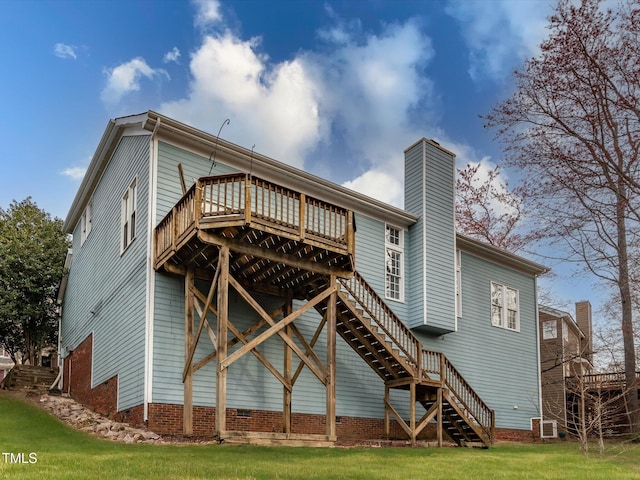 rear view of property with a chimney, a lawn, a wooden deck, and stairs