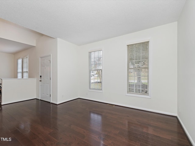 empty room featuring dark wood finished floors, baseboards, and a textured ceiling