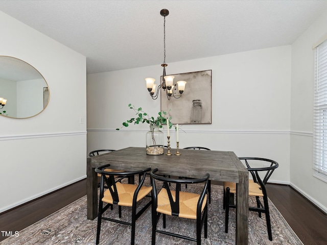 dining space with a chandelier, baseboards, and wood finished floors