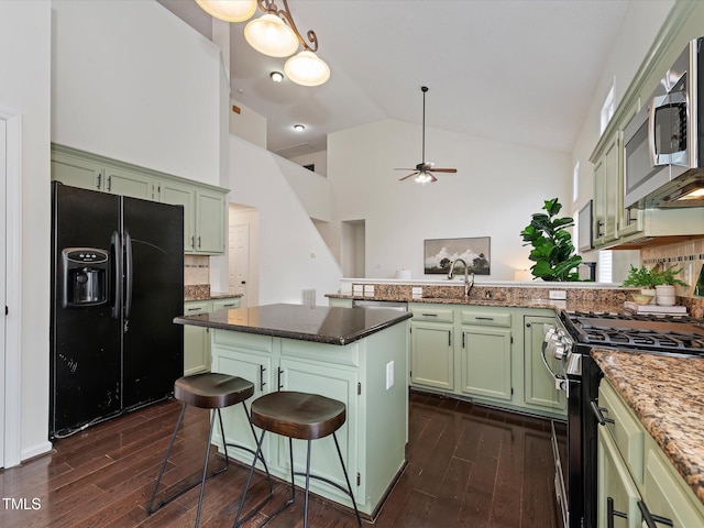 kitchen with green cabinets, a peninsula, gas range oven, and black fridge with ice dispenser