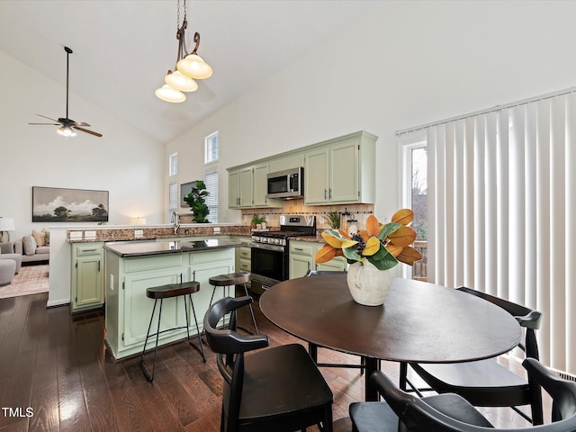 dining room featuring plenty of natural light, high vaulted ceiling, dark wood-style flooring, and a ceiling fan