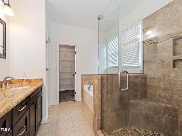 bathroom featuring a spacious closet, a garden tub, a stall shower, tile patterned floors, and vanity