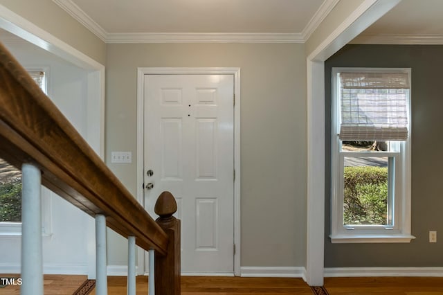 entryway featuring wood finished floors, baseboards, ornamental molding, and stairs