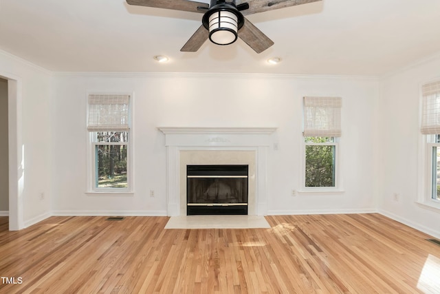 unfurnished living room with a wealth of natural light, a fireplace with flush hearth, and wood finished floors