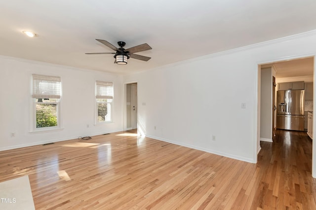 unfurnished room featuring baseboards, a ceiling fan, crown molding, and light wood finished floors